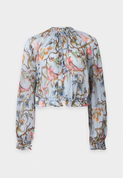 Blouse transparente à manches longues, base bleu clair, imprimé floral coloré, ourlet volanté, encolure froncée et lien à pompon au col.