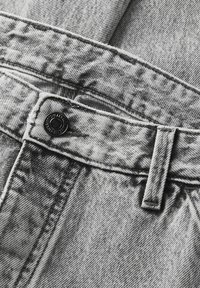 Hallhalli denimkangas, millel on pleekinud, hape-wash muster. Omab musta nupuga kinnitust, vöölõikeid ja kontrastsete õmblemise detailidega.