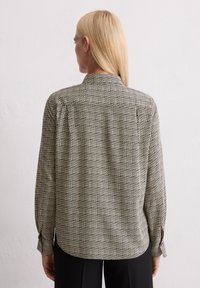 Chemise à manches longues avec un motif géométrique noir et blanc, en tissu doux, avec col et poignets boutonnés. Vue arrière affichée.