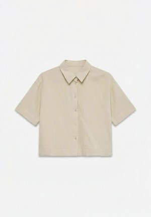 Chemise beige à manches courtes avec boutons et col classique, confectionnée dans un tissu texturé et léger.