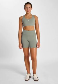 Sport-bh och shorts-set i dämpad grön färg, tillverkat av stretchigt tyg. Bh:n har tunna axelband och shortsen är midjelånga med hög midja.