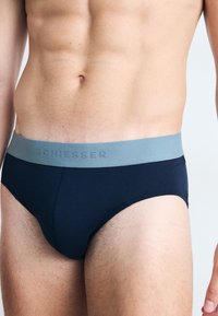 Navy blauwe briefs van zachte stof, met een lichtgrijze elastische tailleband waarop het reliëf van het "SCHIESSER" logo is aangebracht. Glad textuur, aansluitende pasvorm.