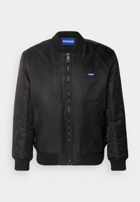 Blouson bomber noir zippé avec col, poignets et ourlet côtelés, orné de petites écussons bleus « HUGO » sur la poitrine et à l’intérieur du col.