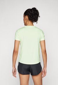 Lys grønn kortermet treningsskjorte med rund hals, laget av glatt materiale, følges av svarte shorts.