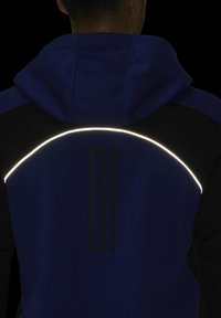 Sweat à capuche bleu fonc é et noir, présentant un motif arc réfléchissant à l'arrière et trois bandes noires disposées verticalement.