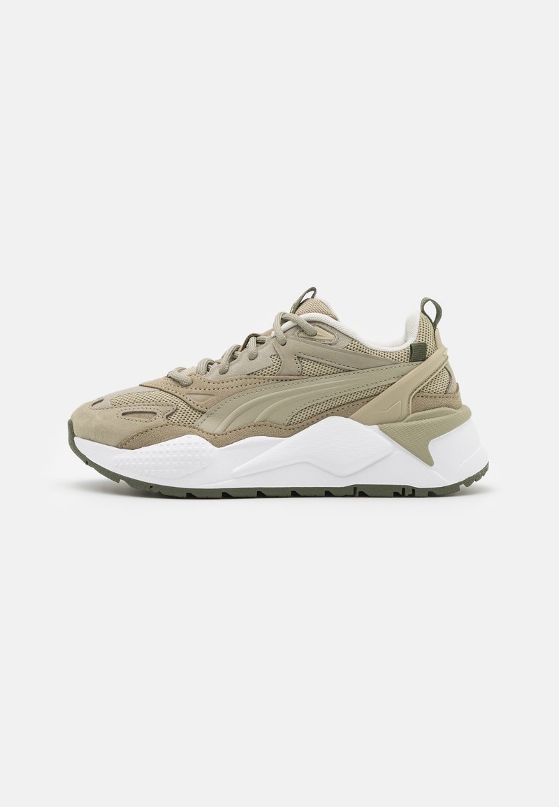 Baskets de sport beige et vert olive avec dessus en mesh et daim, semelle blanche épaisse, fermeture à lacets et languette au talon.