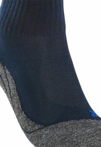 Calcetín azul marino con tejido texturizado, talón reforzado y puño gris. Presenta un acento de logo azul cerca de la base.