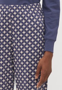 Mörkblå pyjamasbyxor med krämfärgade geometriska mönster, med elastisk midja och mjuk tygtextur.