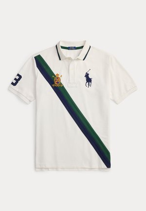 Bela polo majica z zelenimi in mornarsko modrimi diagonalnimi črtami, mornarsko modrim logotipom polo igralca na prsih, številko 3 na rokavu ter vezenim grbom z "20."