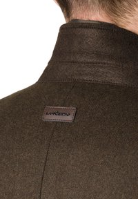 Kurtka z ciemnego brązu z wełny, posiadająca kołnierz o teksturowym wykończeniu oraz skórzaną metkę z nazwą marki "Lancerto" naszytą z tyłu.