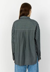 Button-up shirt with a back yoke, black fabric featuring vertical white and colored stripes, long sleeves, and a relaxed fit.