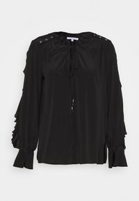 Blouse noire à manches longues, avec des accents volants, un col à nouer et une quincaillerie argentée décorative sur les épaules. Tissu lisse avec une coupe décontractée.