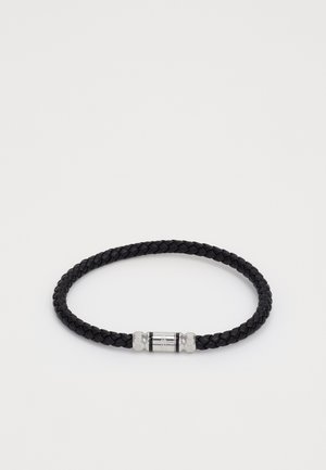 Sort flettet læderarmbånd med en metalspænde, der har indgraverede detaljer og en poleret sølvaccent.
