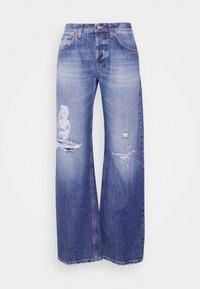Jean bleu à jambes larges avec taille haute, patchs usés sur la cuisse gauche et le genou droit, et légère décoloration sur l'avant des cuisses.
