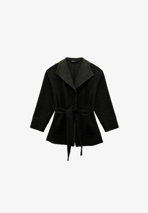 Cardigan en laine noire avec un col large, des manches longues et une ceinture nouée à la taille, présentant une finition texturée et deux poches frontales.