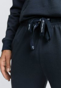 Marineblaue Jogginghosen aus texturiertem Stoff, mit einem Kordelzugbund und "TOM TAILOR"-Logo sowie seitlichen Eingrifftaschen.