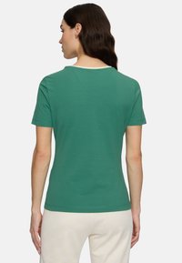 T-shirt verde a maniche corte con collo a giro, texture liscia e design semplice. Il retro presenta un colore uniforme senza motivi.