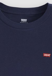 T-shirt en coton bleu marine à texture côtelée, col rond, avec un petit logo rouge Levis sur la poitrine gauche.