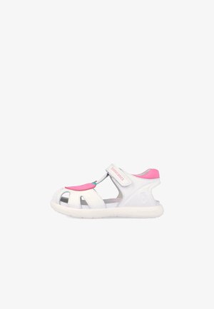 Sandalia abierta para niños en blanco y rosa con correa de velcro y suela acolchada.