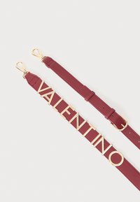Maroon nahka vyö, jossa kultasävyinen teksti "VALENTINO", sileä pinta ja metalliklipit kummassakin päässä.
