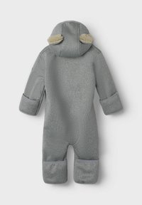 Combinaison de ski grise en une pièce avec une finition texturée, capuche bordée de fourrure et poignets roulés. Comprend des ouvertures pour les pieds et les mains renforcées.