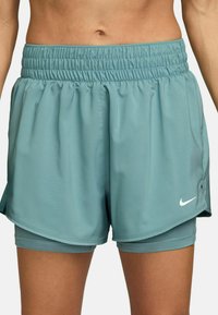 Pantalones cortos deportivos de color azul claro con una cinturilla elástica, con un diseño en capas y un pequeño logo blanco de Nike en la parte inferior frontal.