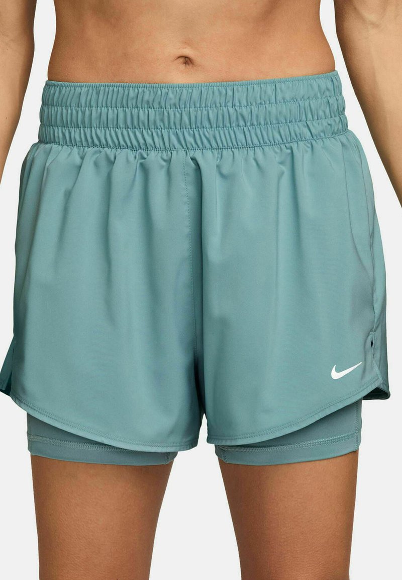 Pantalones cortos deportivos de color azul claro con una cinturilla elástica, con un diseño en capas y un pequeño logo blanco de Nike en la parte inferior frontal.