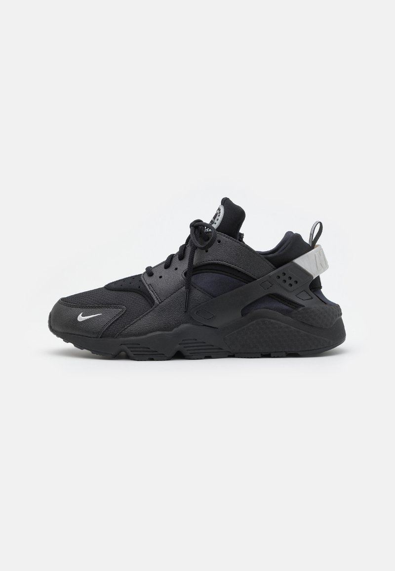 Black and dark gray Nike athletic sneaker with mesh and suede panels, laces, and a thick rubber sole on a white background.