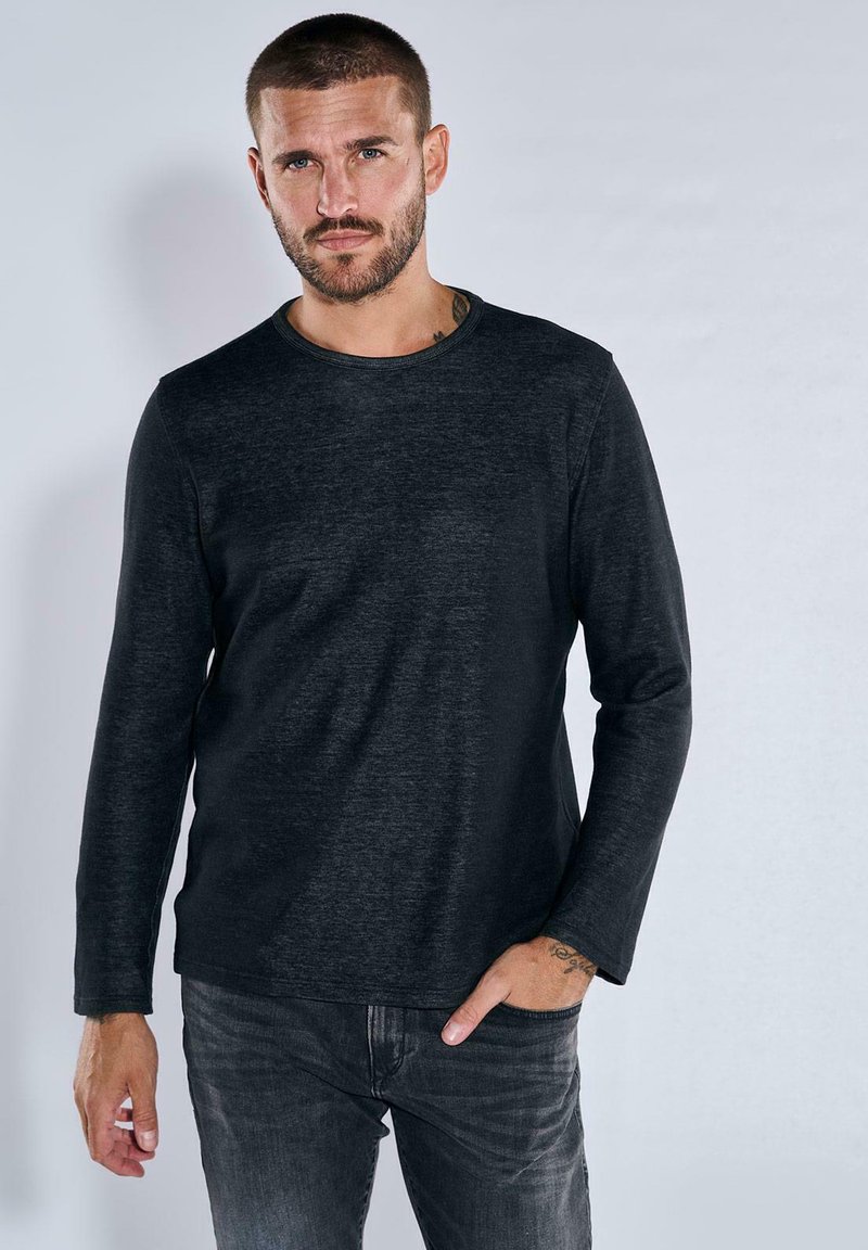 Schwarzes Langarm-T-Shirt mit rundem Ausschnitt, aus einem strukturierten Stoff gefertigt, mit lockerem Schnitt und subtilen Melange-Muster.