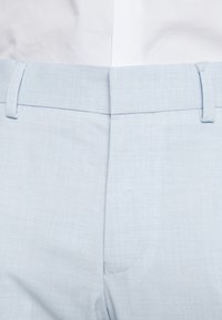 Hellblaue Stoffhosen mit strukturiertem Finish, flachem Bund, Gürtelschlaufen und subtilen Nähten. Taillierte Passform mit seitlichen Taschen.
