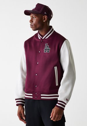 Veste varsity bordeaux avec manches en cuir blanc, poignets et col côtelés. Présente le logo "LA", des boutons-pression et deux poches latérales.