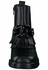Botín negro de cuero con detalles de flecos y un acento de cadena negra brillante. Textura suave con puntera redonda y suela de plataforma baja.