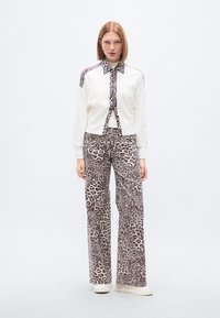 Λευκό μακρυμάνικο τοπ με λεοπάρ λεπτομέρειες, συνδυασμένο με παντελόνι φαρδύ με λεοπάρ σχέδιο. Λείο ύφασμα, χαλαρός σχεδιασμός.