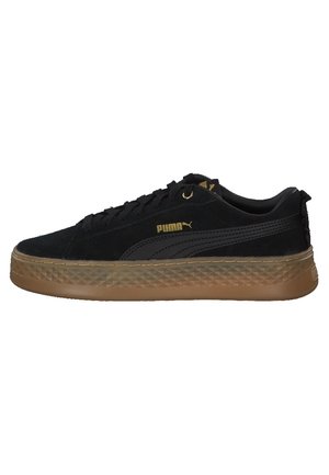 Czarny zamszowy sneaker Puma z gumową teksturowaną podeszwą, złotym logo Puma po boku, czarnymi sznurowadłami i wyściełanym kołnierzem.