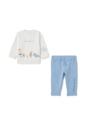 Witte sweatshirt met cartoonfiguren, met de tekst "volg je hart", gecombineerd met lichtblauwe sweatpants met een "Winnie the Pooh" print.