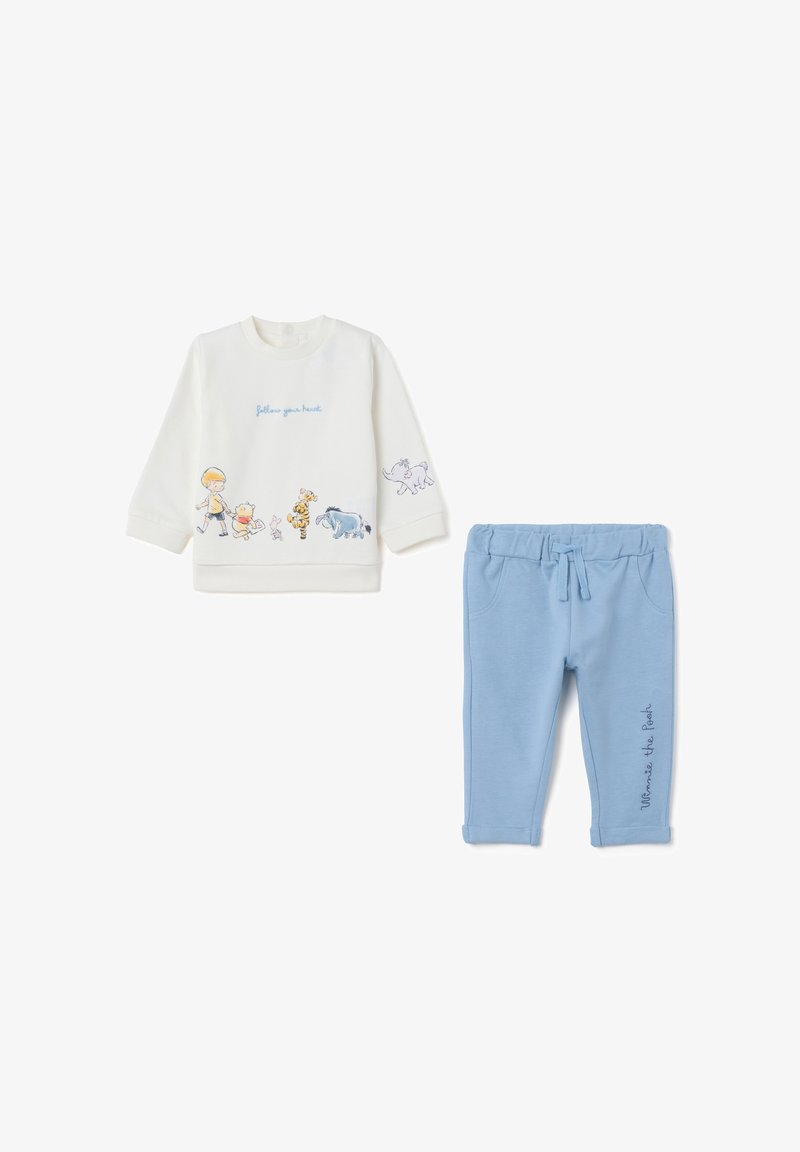 Sudadera blanca con personajes de dibujos animados, con el texto "sigue tu corazón", combinada con pantalones de chándal azul claro con un estampado de "Winnie the Pooh".
