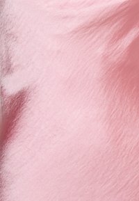 Tecido de veludo rosa suave com uma textura suave, exibindo variações sutis de brilho e profundidade, adequado para estofos ou moda.