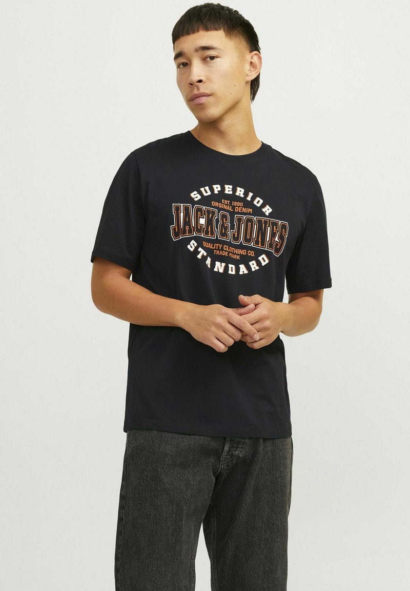 Sort bomulds t-shirt med rund halsudskæring og korte ærmer, der har et grafisk print i orange og hvid med teksten "JACK & JONES STANDARD."