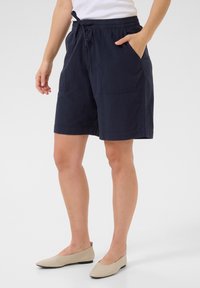 Marineblaue Baumwollshorts mit einem elastischen Bund, Kordelzug und zwei Vordertaschen, die eine entspannte Passform und eine glatte Textur bieten.