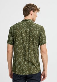 Camicia a maniche corte in tessuto verde oliva, con un motivo di foglie bianche. Collo classico e vestibilità comoda con orlo dritto.
