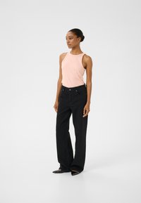 Roze mouwloze top met een ribbeltextuur, gecombineerd met hoge zwarte wijde jeans en puntige zwarte flats. Eenvoudig ontwerp, geen patronen.