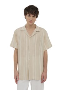 Camicia a maniche corte beige a righe con una vestibilità ampia, realizzata in un tessuto leggero e caratterizzata da un colletto a punte e bottoni bianchi.