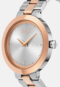 Ümar käekell hõbedase sihini, roosa kullaga äärise ja kellanäppudega, neli teemanditunnistajat ning kahetooniline metallist link-riba.