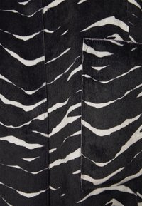 Schwarz-weißes Gewebe mit einem Zebramuster, weiche Textur, mit hellen und dunklen Streifen, die ein kontrastierendes Design bilden.