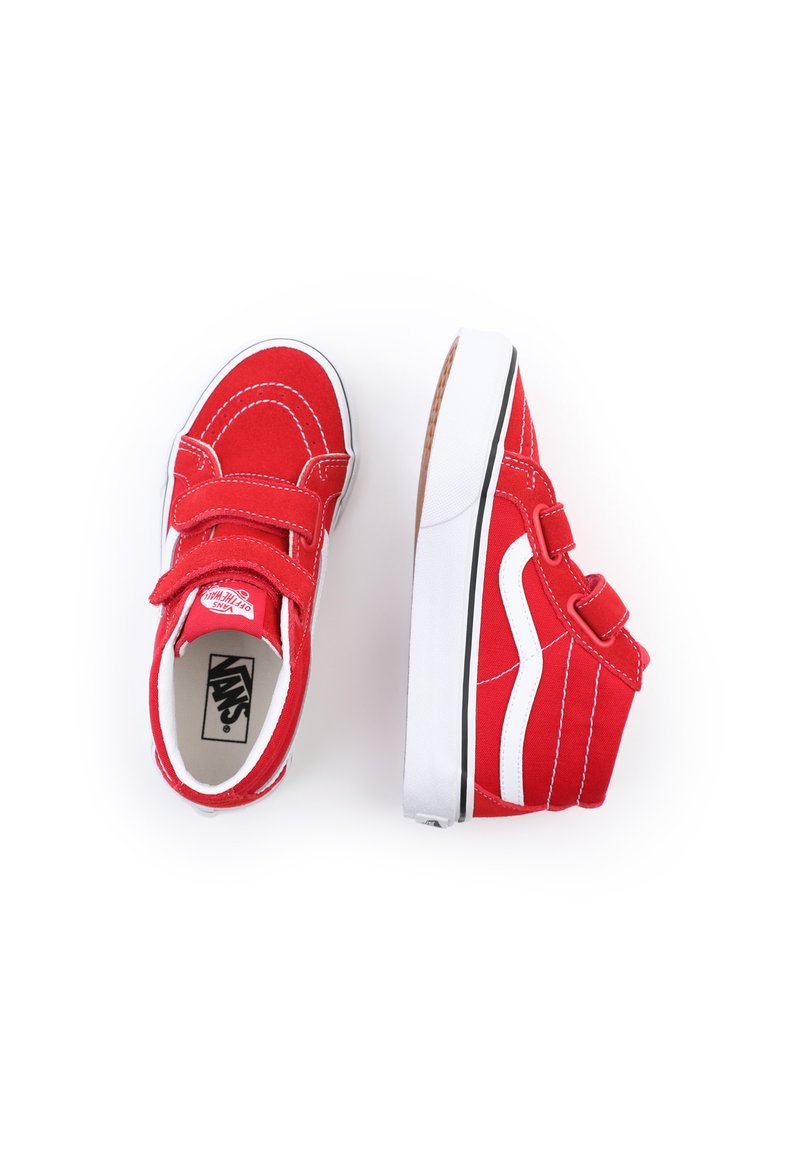 Chaussures en toile rouges avec des accents blancs, dotées de deux bandes Velcro, d'une pointe arrondie et d'une semelle en caoutchouc plate avec une texture antidérapante.