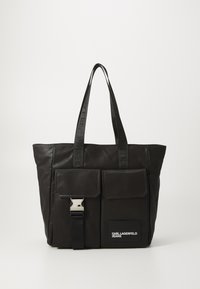 Svart läder tote-väska med två framfickor, en silvrig spänne och prägling på remmarna. Har en "KARL LAGERFELD JEANS"-logotyp i vitt.