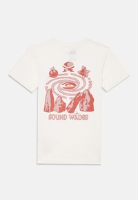 T-shirt in cotone color crema con una stampa grafica rossa che presenta montagne astratte, pianeti e il testo "SOUND WAVES." Maniche corte, colletto a girocollo.