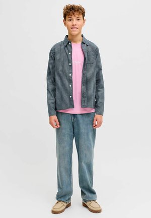 Camicia a quadri blu navy e bianca, indossata sopra una maglietta rosa chiaro; abbinata a jeans di denim azzurri e scarpe beige.