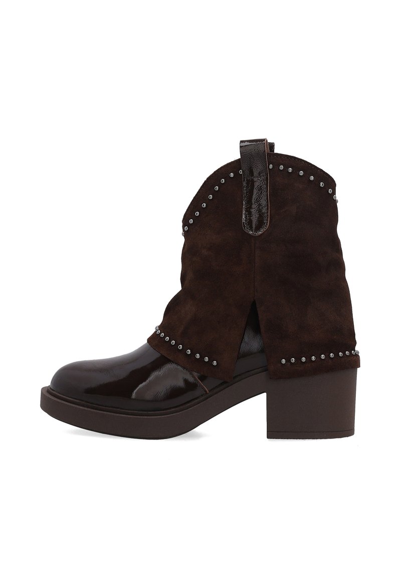 Brązowe zamszowe botki za kostkę z błyszczącym lakierowanym noskiem, z dodatkami w formie ćwieków i słupkowym obcasem. Tylna pętelka ułatwiająca zakładanie.