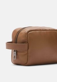 Neceser de cuero marrón con forma rectangular, costuras sutiles, cierre de cremallera en la parte superior y un asa lateral para un fácil transporte.